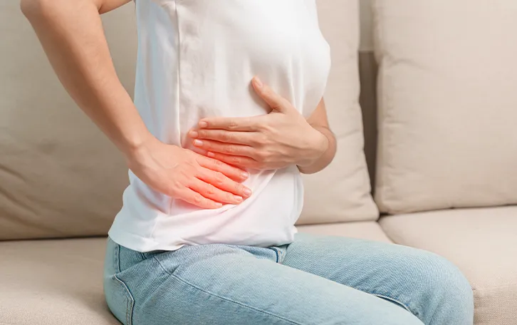 Eine weibliche Person hält sich die rechte Seite. Schemenhaft mit rotlicher Färbung dargestellt