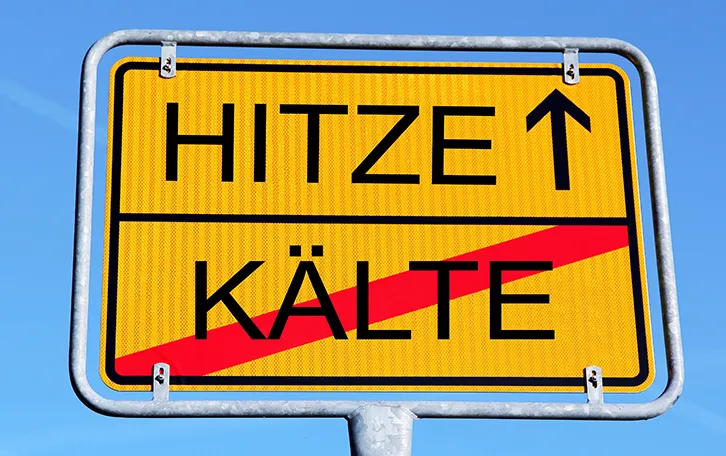 Ein Ortsausgangsschild mit Oben Hitze und unten durchgestrichen Kälte stehend