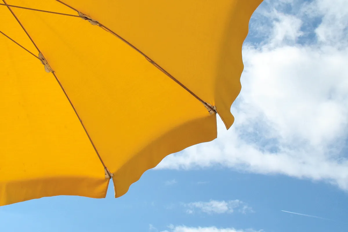 Mallorca Akne Anwendungstipps Hydrogalen Ein gelber Sonnenschirm vor einen leicht bewölktem blauen Himmel