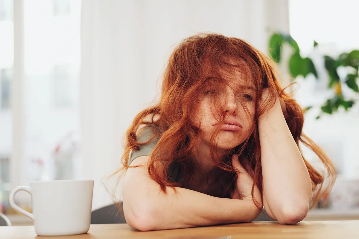 Stress erheblicher Einfluss bei Hautausschlag Eine weibliche Person stützt den Kopf auf einen Arm und sieht gestresst aus